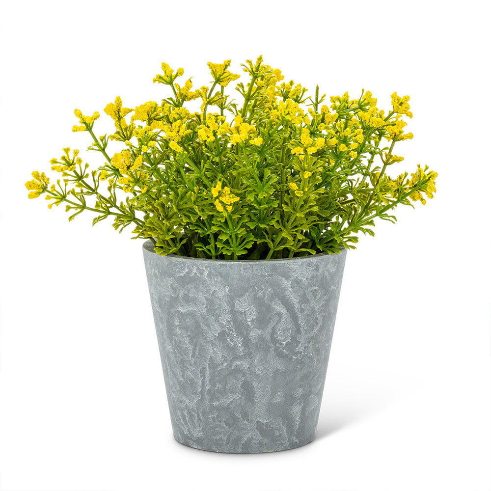 Plante artificielle et fleurs jaunes dans un pot imitation ciment.